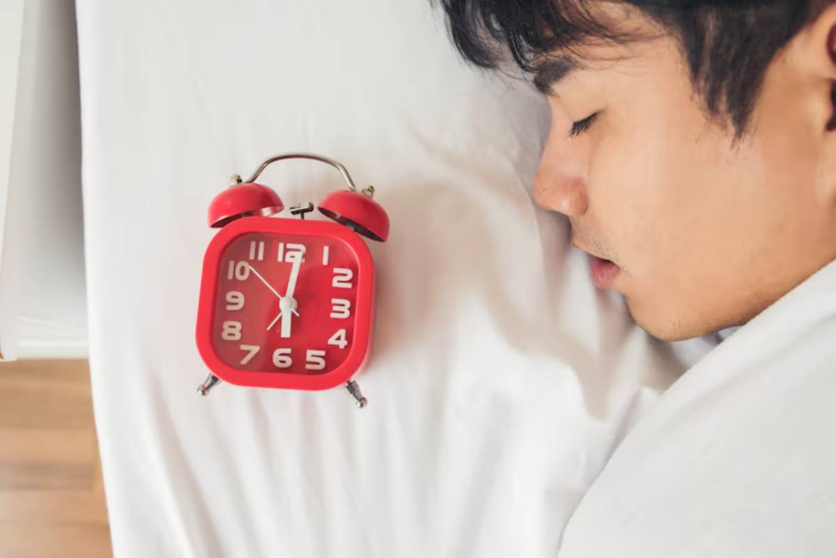 A red alarm clock rests on a person's white shirt, indicating the time with large, clear numbers.