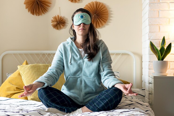 middle aged woman pajamas sleep mask sitting relaxed on bed